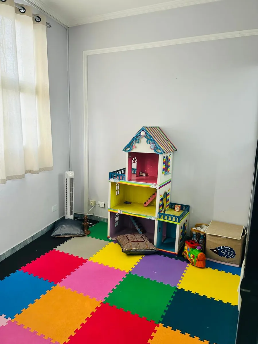Espaço infantil com piso colorido e casa de bonecas em Jandira